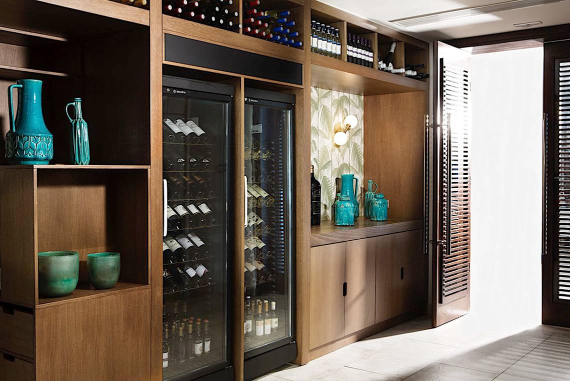 Ein holzschrank mit einem weinkühlschrank und mehreren flaschen darin.
