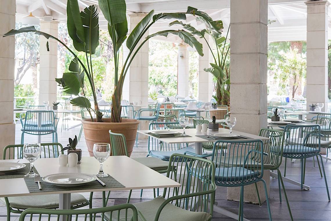 Innenbereich des Cretan Malia Park Hotels mit blauen Stühlen und Tischen.