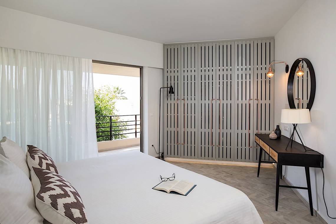 Ein modernes Hotelzimmer im Cretan Malia Park mit einem Bett, Büchern und einem eleganten Design.