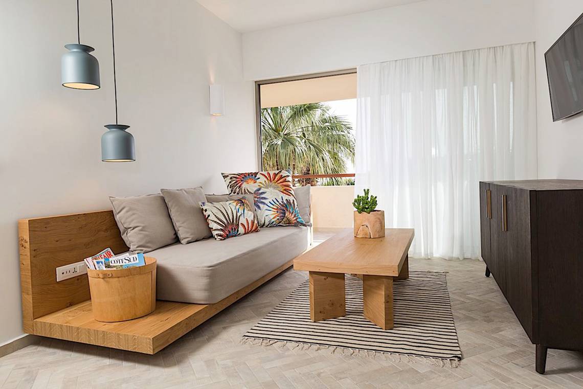Ein Hotelzimmer mit einem Sofa, Tisch und Couchtisch neben einer Terrasse