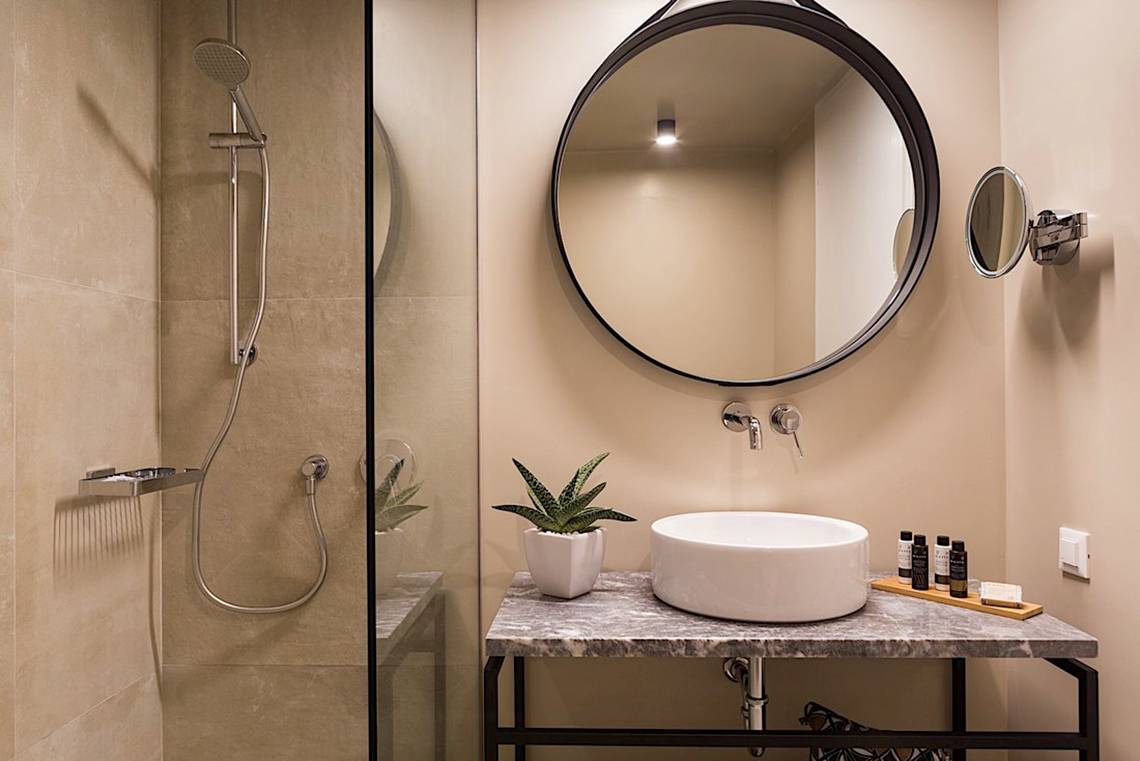 Badezimmer im Cretan Malia Park Hotel mit Dusche, Spiegel und Waschbecken.