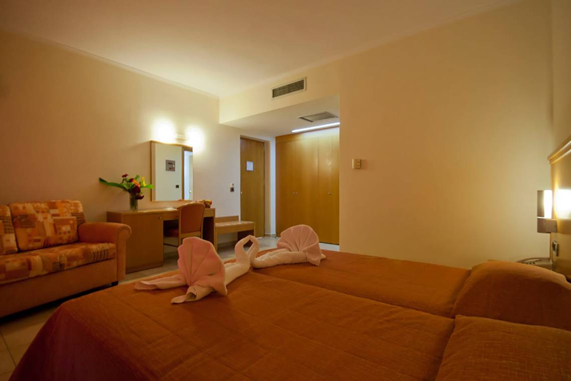 Zimmer im Tigaki Beach Hotel mit zwei Betten und einem Sofa.