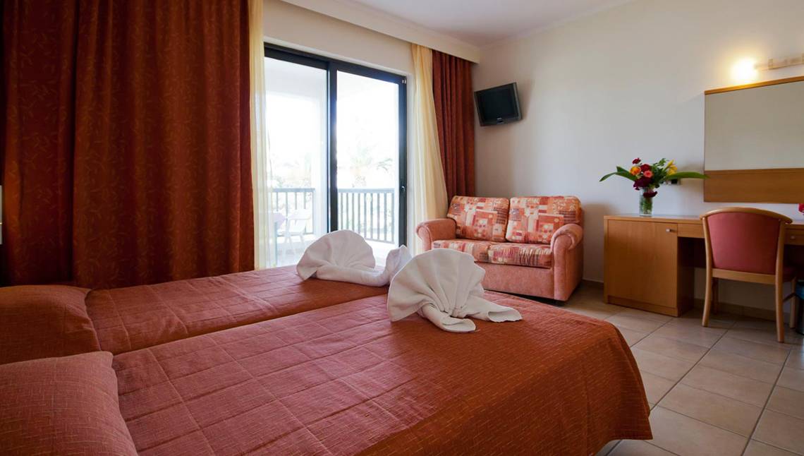 Hotelzimmer mit Balkon und Doppelbett im Tigaki Beach Hotel.