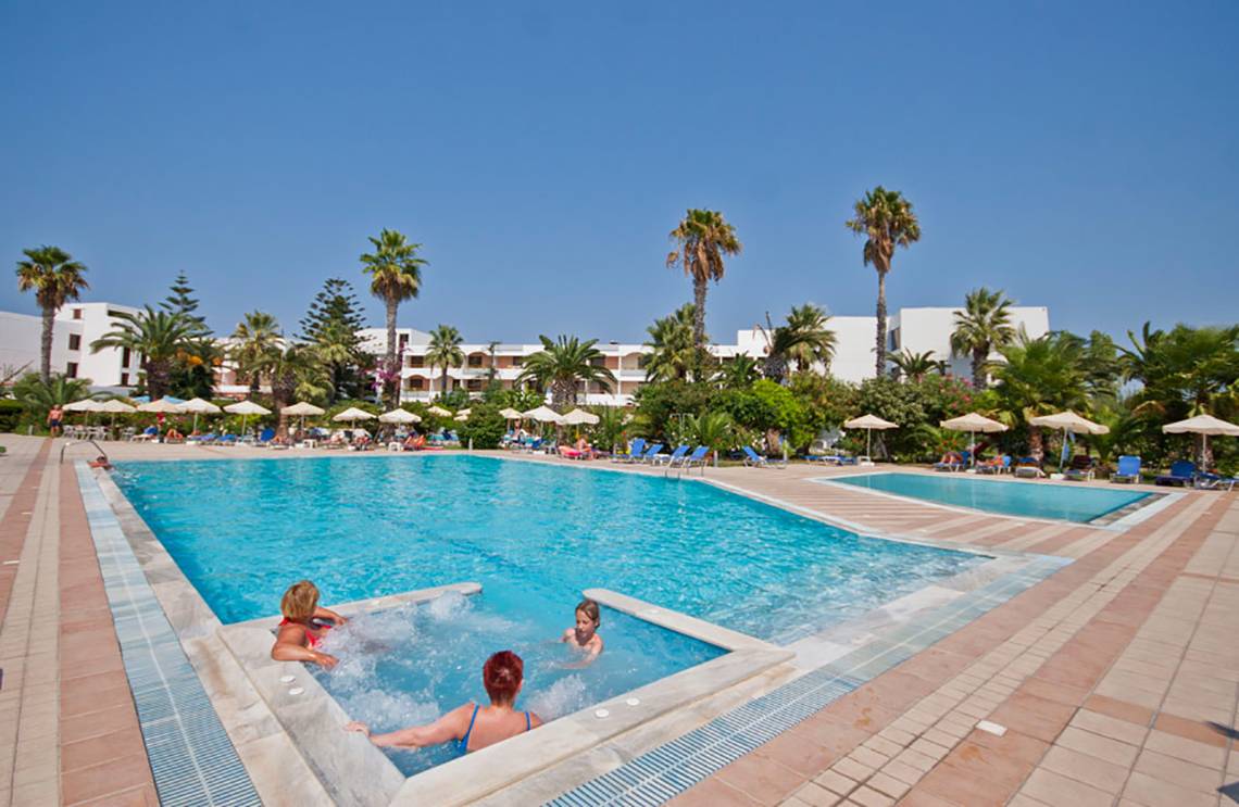 Familien genießen das Schwimmbecken im Tigaki Beach Hotel bei blauem Himmel