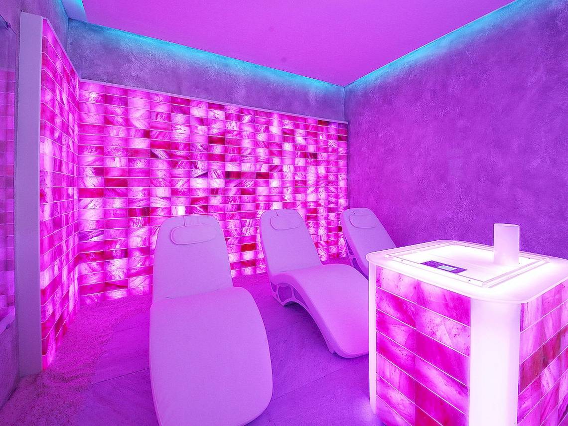 Innenraum des Maritim Hotel Paradise Blue Albena mit rosa beleuchteten Wänden und drei Liegestühlen.