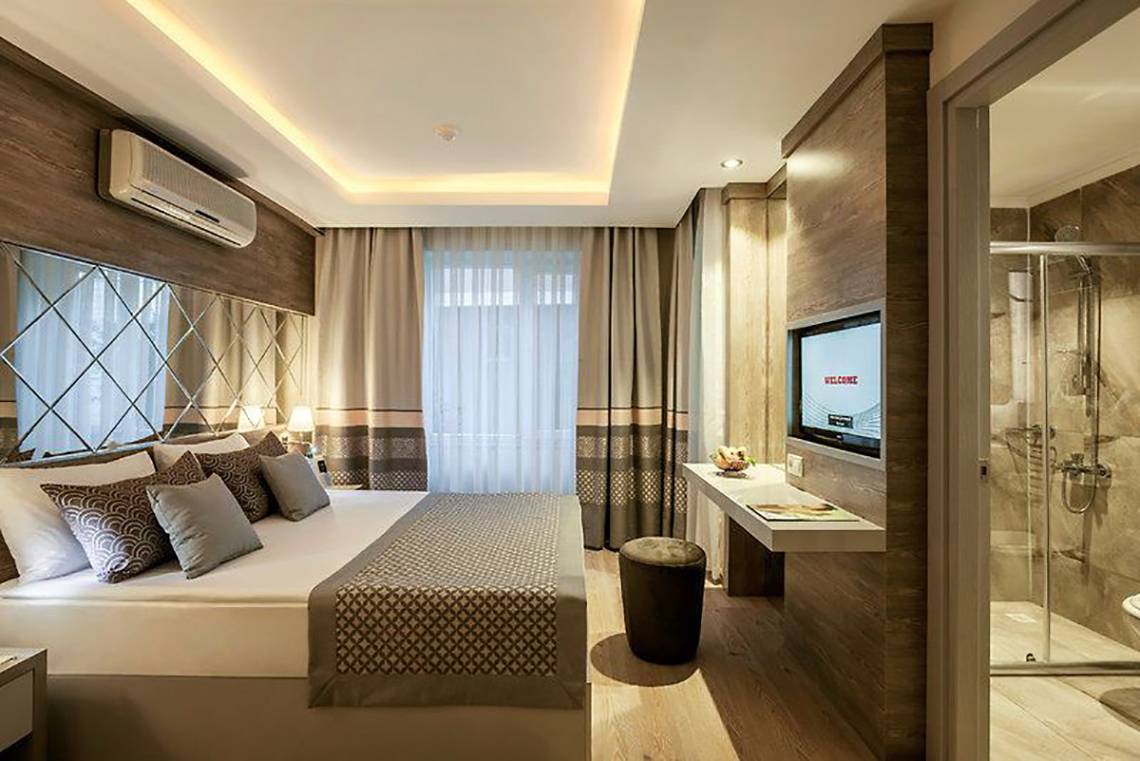 Schlafzimmer im Turan Prince Hotel mit Doppelbett, Fernseher und Dusche.
