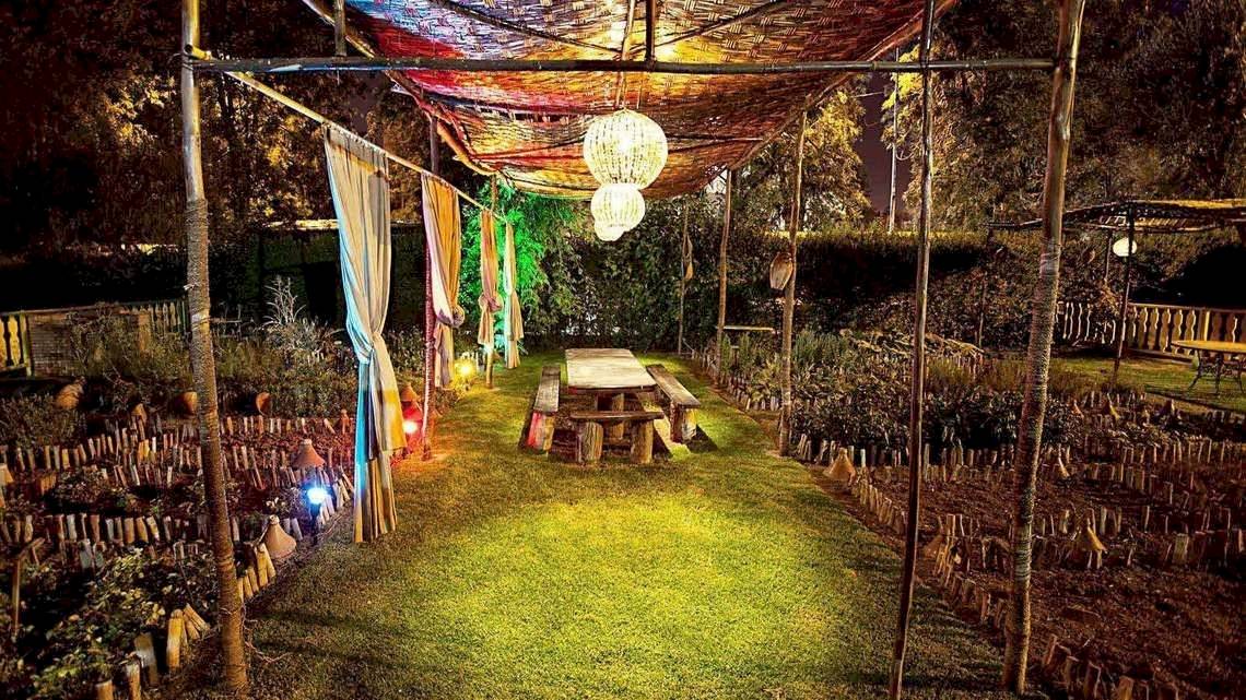 Gartenbereich des Le Meridien N'Fis Hotels bei Nacht mit einem Holztisch und Stühlen.