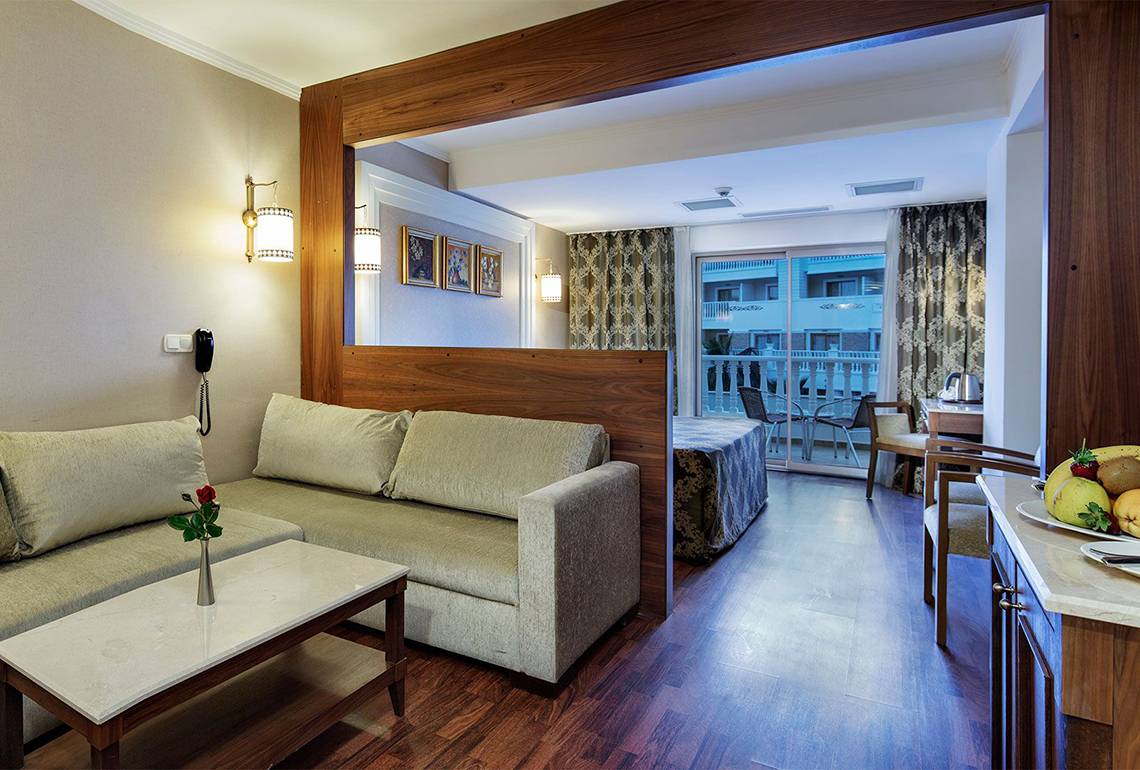 Innenansicht eines Zimmers im Alba Queen Hotel mit Sofa, Tisch, Balkon und Bett