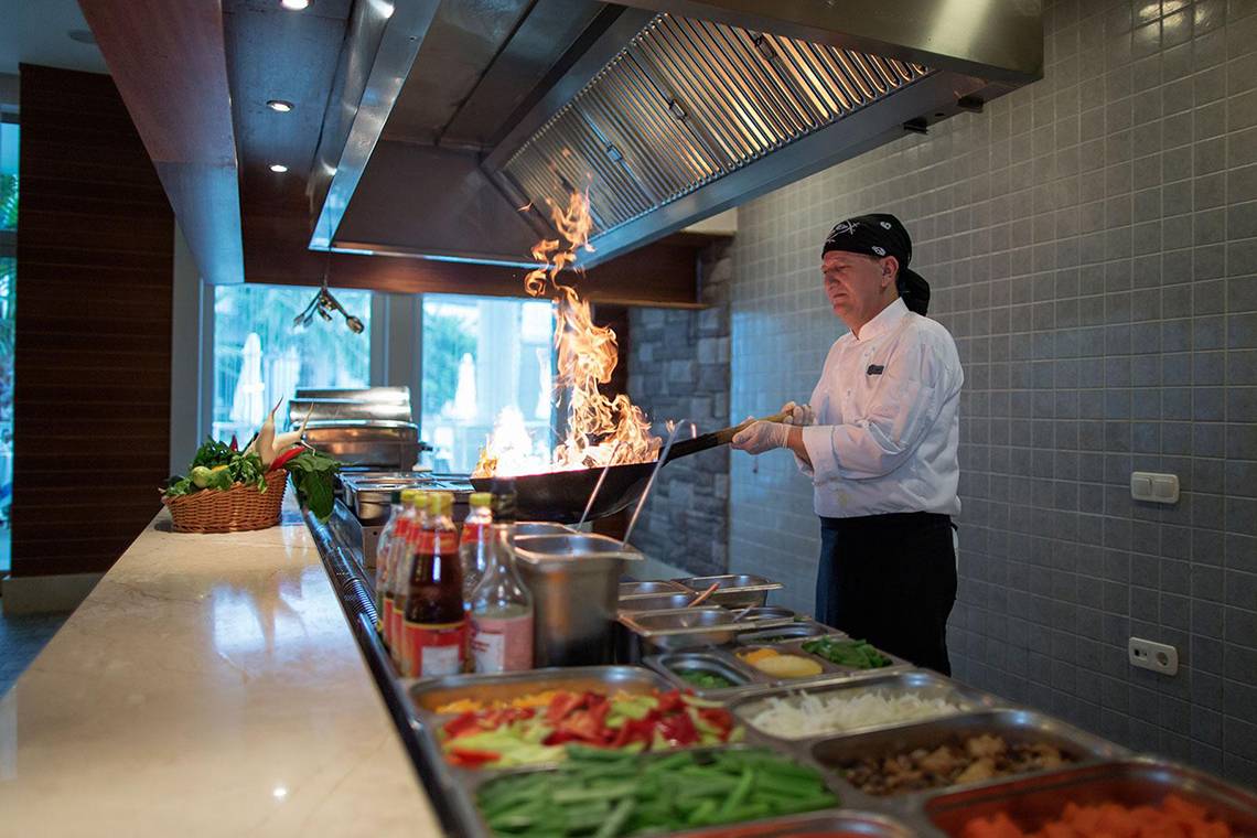 Koch in der Küche, der mit Feuer kocht, im Alba Queen Hotel