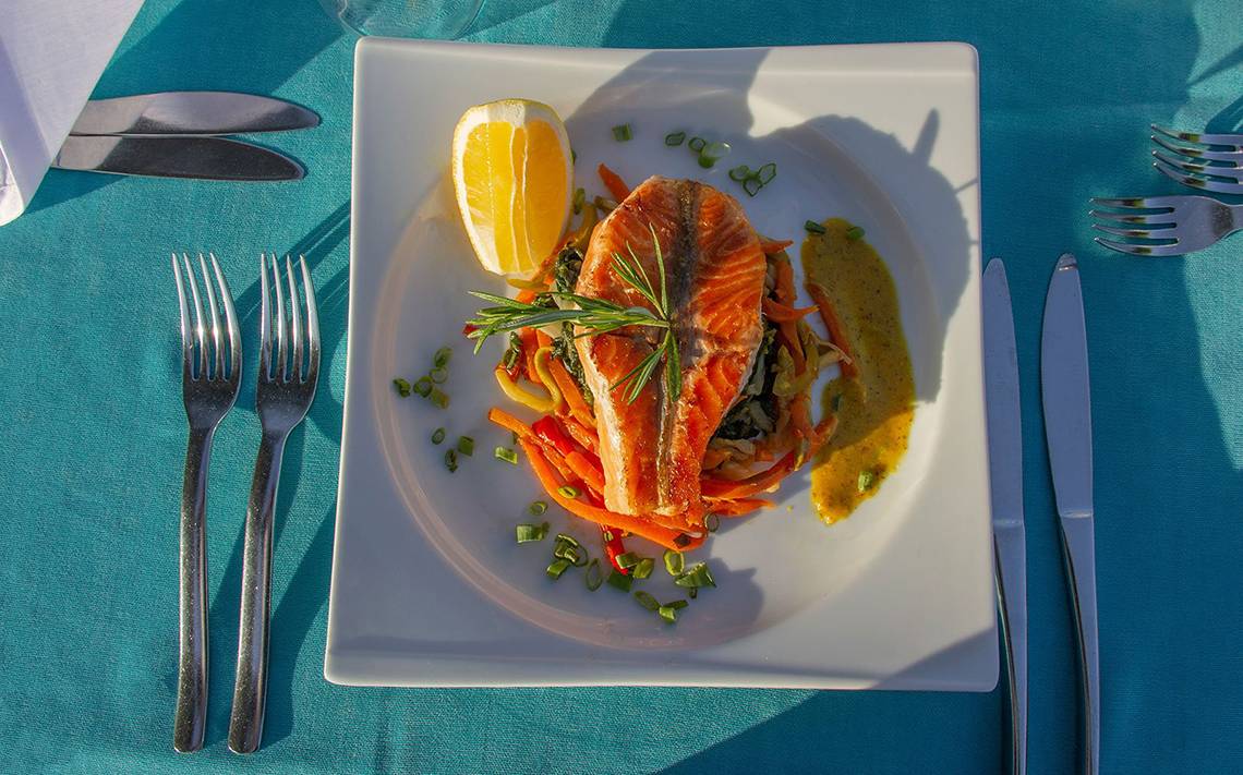 Gebratener Lachs auf einem weißen Teller mit Gemüse im Hotel Alba Queen.