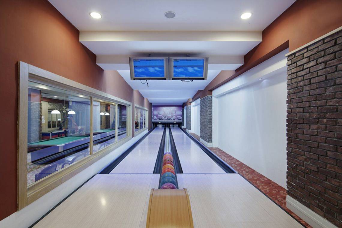 Bowlingbahn im Alba Queen Hotel mit zwei Monitoren und Bowlingkugeln in einer Reihe.