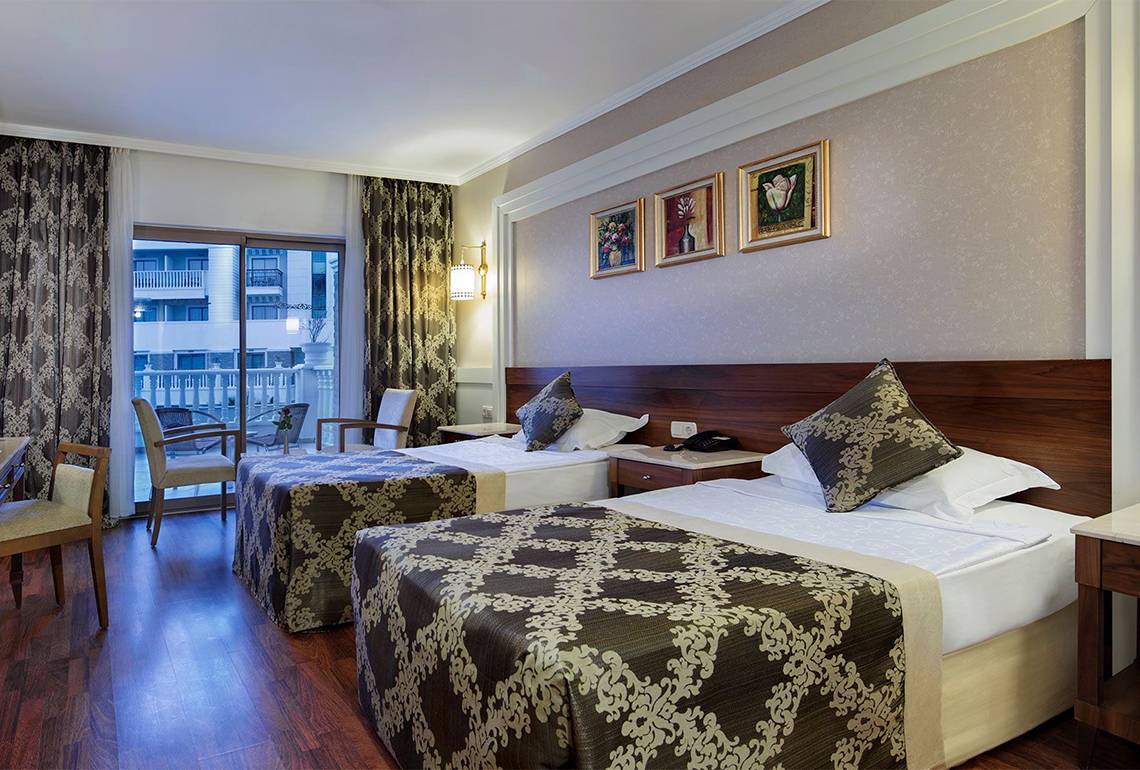 Hotelzimmer des Alba Queen Hotels mit zwei Betten, einem Balkon und Blick auf ein anderes Gebäude.