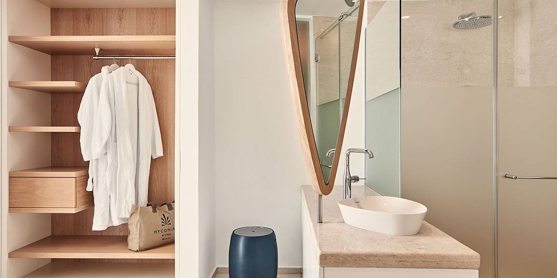 Badezimmer mit offenem Kleiderschrank, Robe, und Waschbecken im Hotel Myconian Kyma.