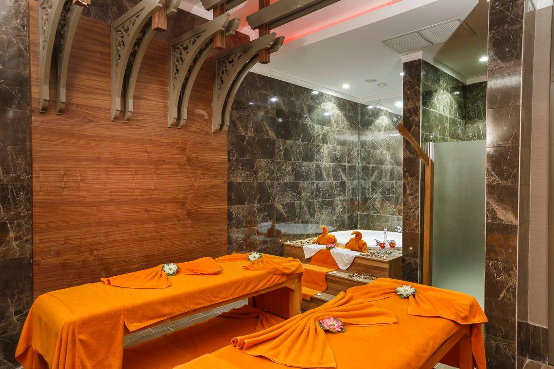 Spa-Behandlungsraum im Well Palace Side Hotel mit zwei Massagetischen und Marmorwänden.