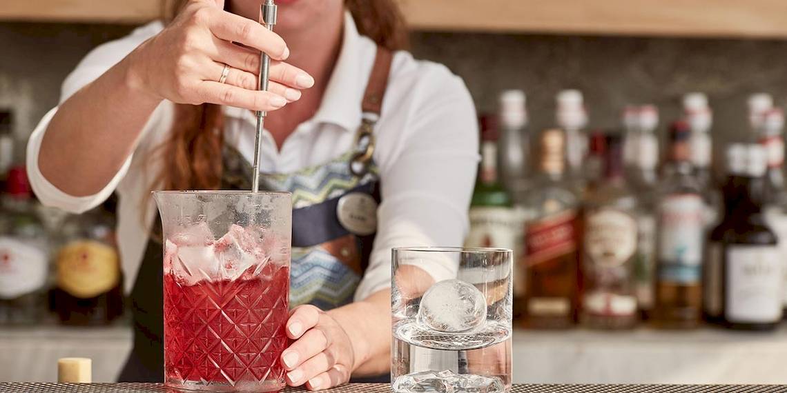Frau mischt einen Cocktail am Tresor Bar im Myconian Kyma Hotel