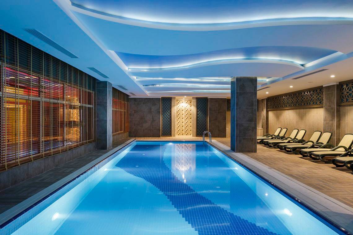 Innenpool des Well Palace Side Hotels mit geometrischen Deckenverzierungen und Sonnenliegen