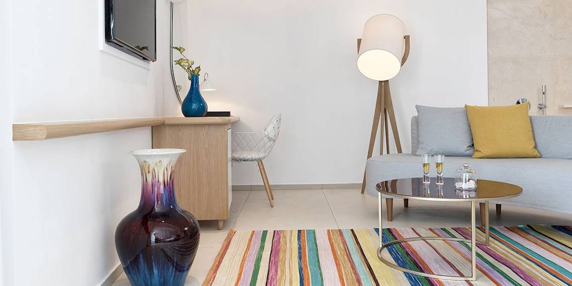 Inneneinrichtung des Myconian Kyma Hotelzimmers mit Schreibtisch, Stuhl, Fernseher, Lampe, Couch und Tisch.