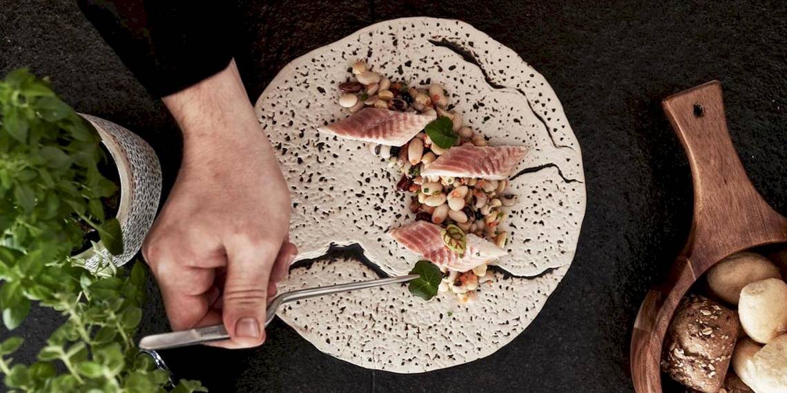 Ein Teller mit Essen von Myconian Kyma, bestehend aus Fisch, Bohnen und anderen Zutaten.