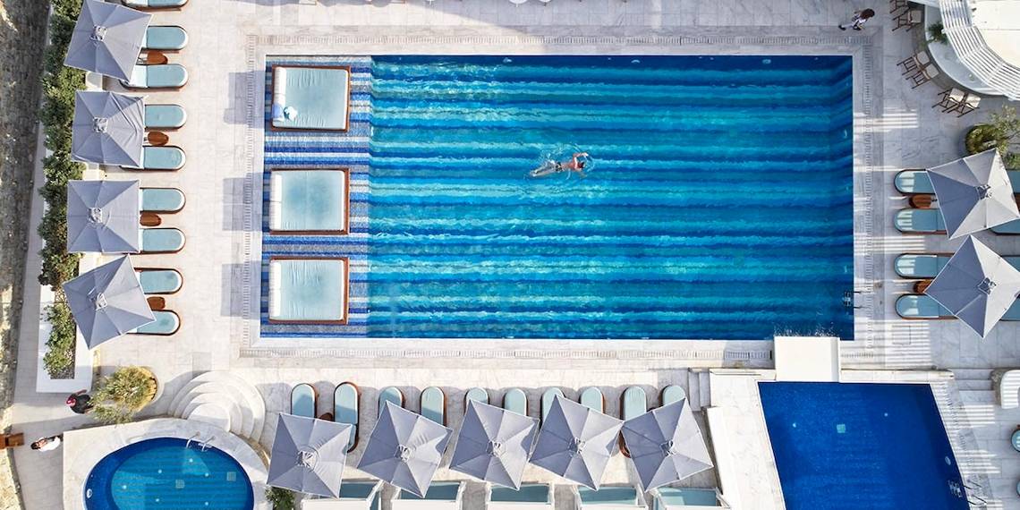 Luftaufnahme des Schwimmbeckens im Myconian Kyma Hotel mit Sonnenliegen und Sonnenschirmen