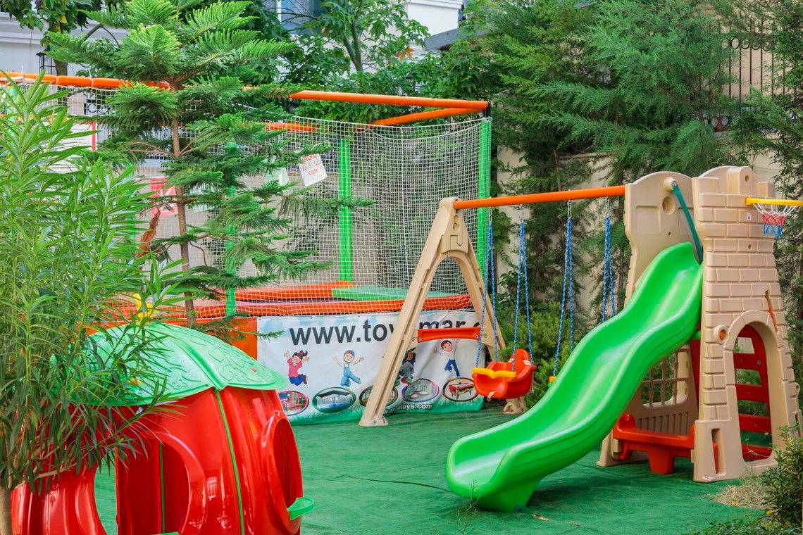 Kinderspielplatz im Freien im Well Palace Side Hotel mit Rutsche und Schaukeln.