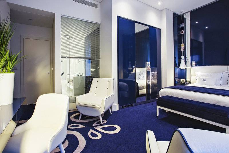 Portugal Boutique Hotel Schlafzimmer mit blauem Teppich und weißen Möbeln.