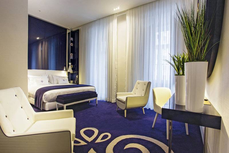 Schlafzimmer im Portugal Boutique Hotel mit Doppelbett, Stühlen und Pflanzen.