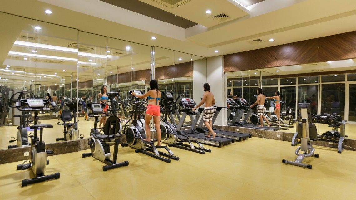 Innenansicht des Fitnesscenters im Well Palace Side Hotel mit mehreren Cardiogeräten und spiegelnden Wänden.