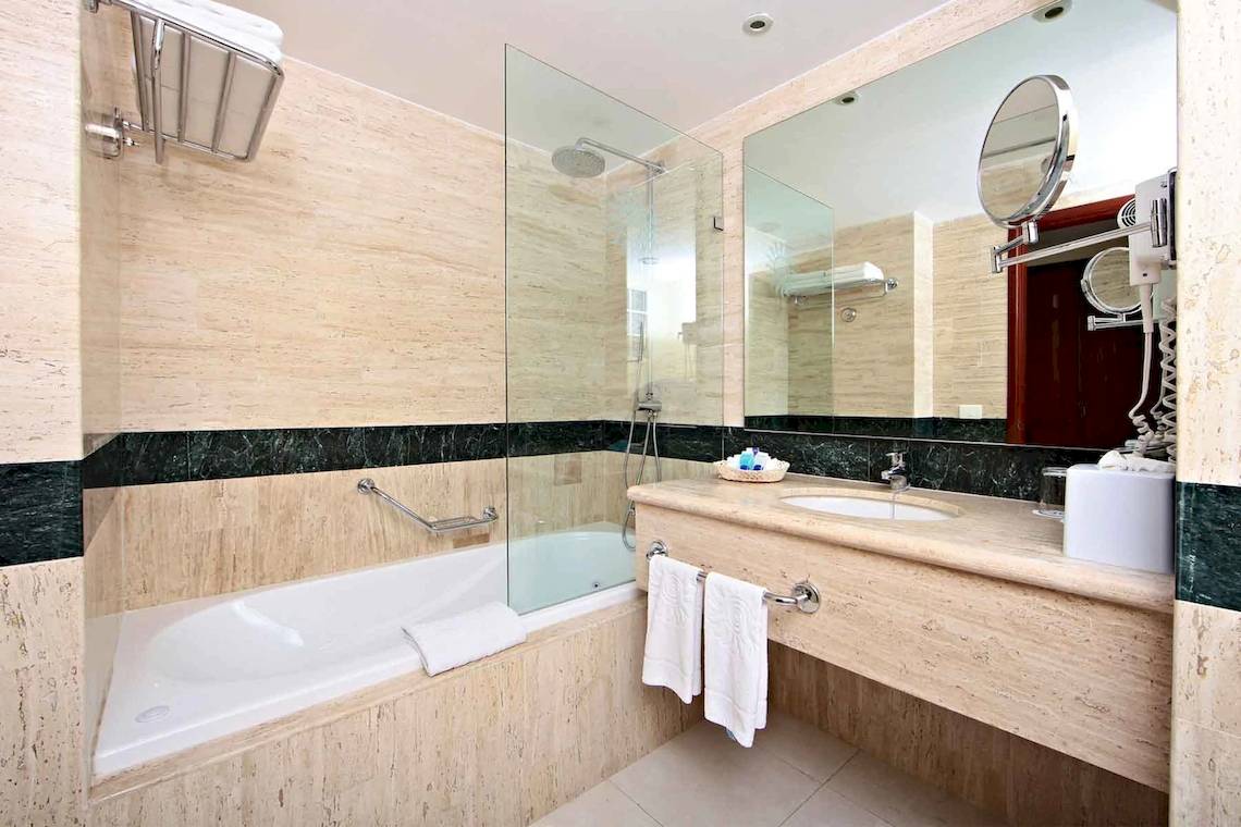 Ein Badezimmer mit einer Badewanne, einem Spiegel und einem Waschbecken.