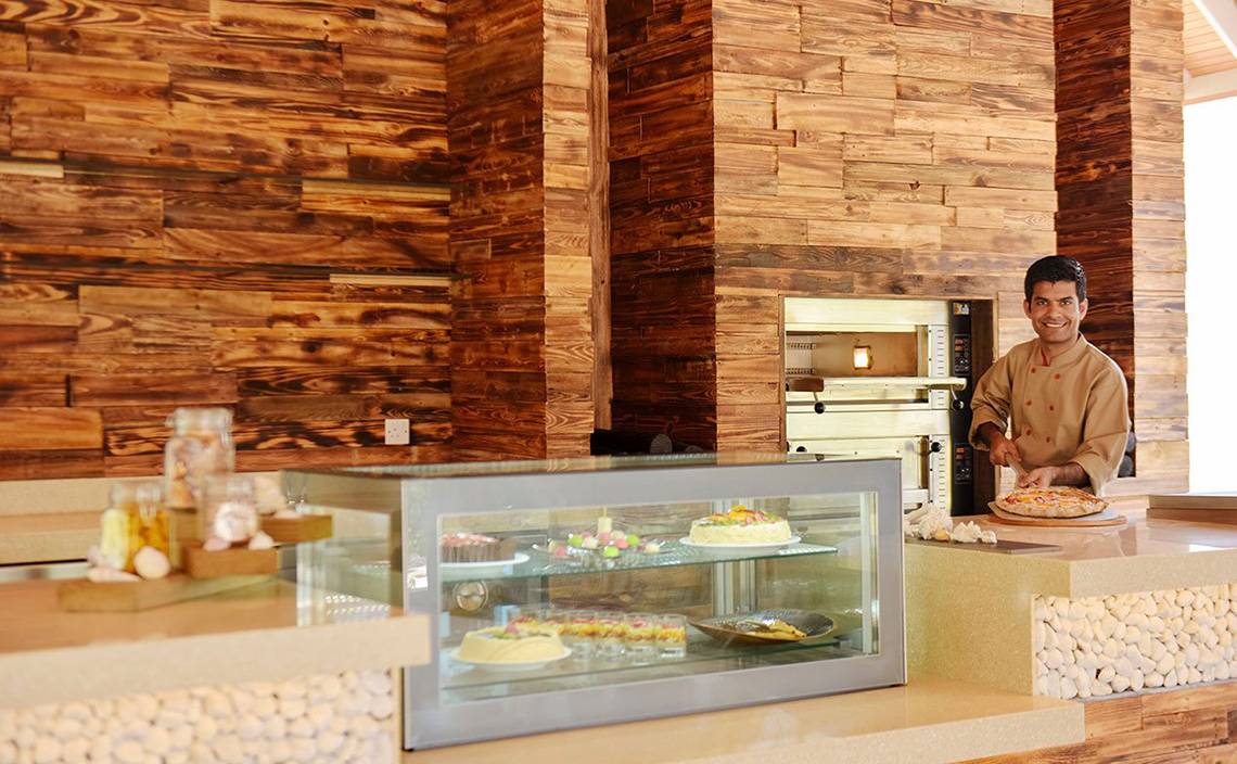 Koch mit Pizza in der Küche des Dhigali Maldives Hotels
