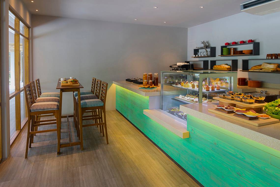 Frühstücksbereich im Dhigali Maldives Hotel mit Esstischen und Buffet