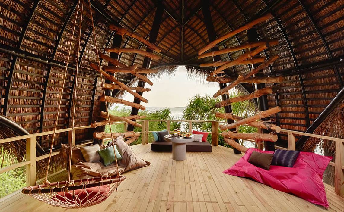 Innenansicht des Dhigali Maldives Hotels mit Holzbalkendecke und Blick aufs Meer.