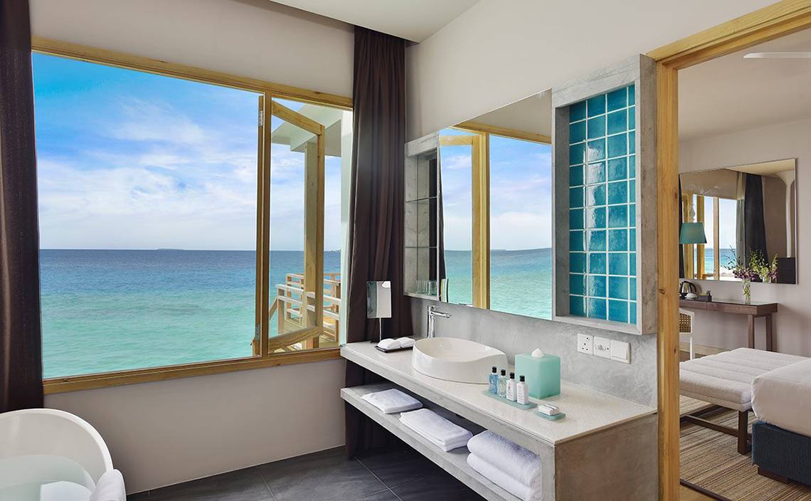 Badezimmer im Dhigali Maldives Hotel mit Aussicht auf das Meer.