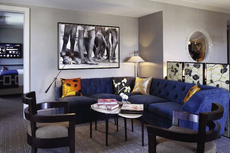 Hotelzimmer mit blauer Couch, Tisch, Kissen und Dekor.