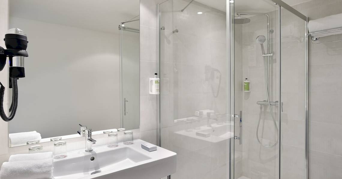 Ein modernes Badezimmer mit einer Glasdusche, einem Waschbecken und einem Spiegel im Sol Principe Hotel.