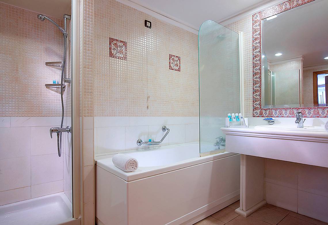 Badezimmer im Aldemar Knossos Royal Resort mit Badewanne, Dusche und Waschbecken.