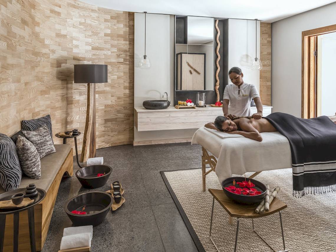 Massagebehandlung im Hotel Shangri-La Le Touessrok mit einem Kunden, der sich entspannt auf einem Massagebett befindet.