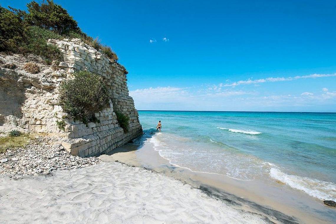 Strand mit Kliff und einer Person, die am Wasser steht