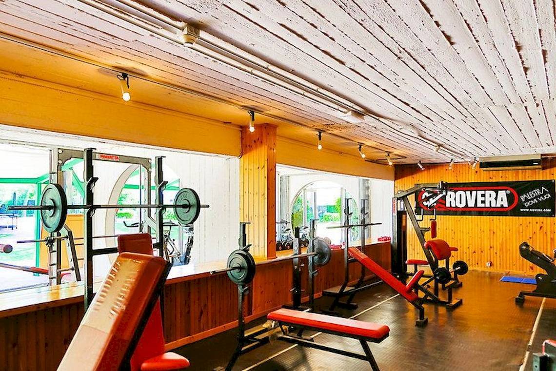 Fitnesscenter im VOI Alimini Resort mit verschiedenen Geräten und einer gelben Wand.
