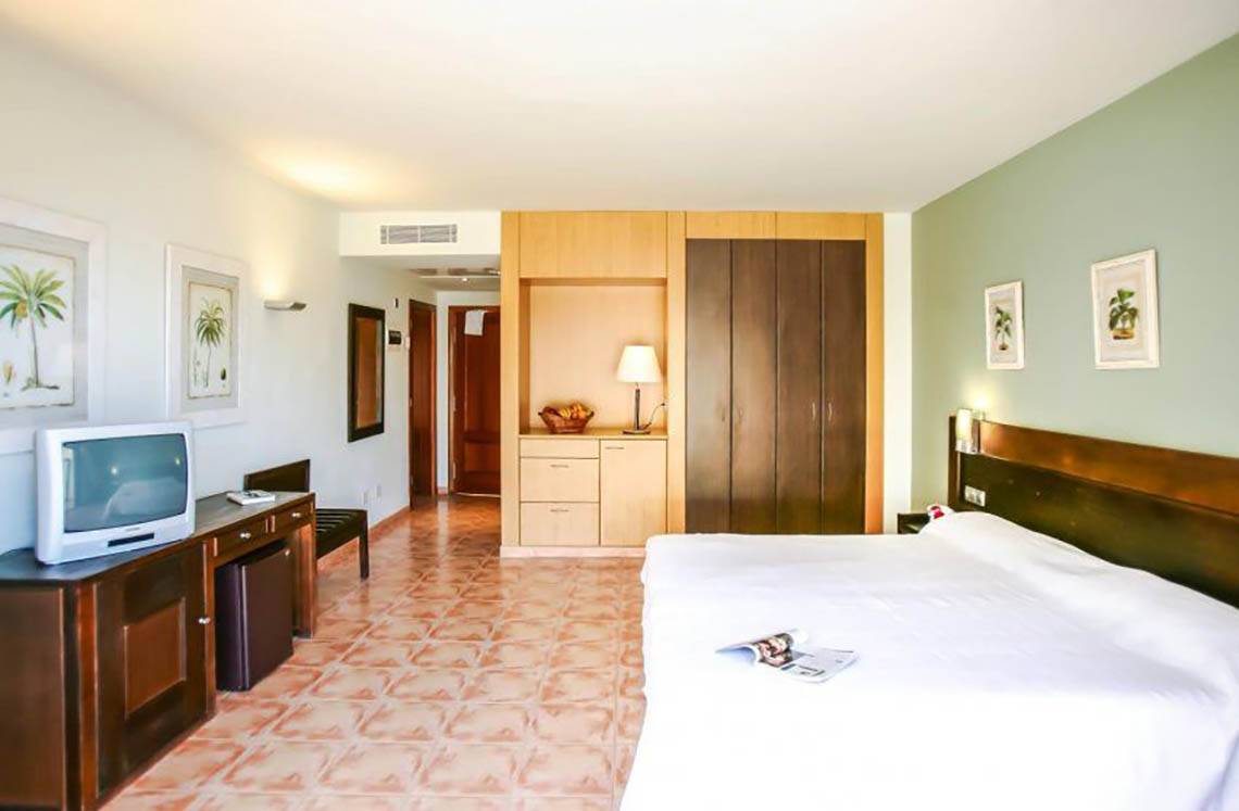 Innenansicht eines Hotelzimmers im LIVVO Lago Taurito mit Bett, Fernseher, Nachttisch und Kleiderschrank.