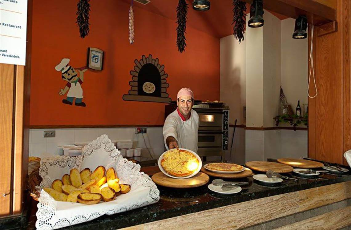 Mitarbeiter im LIVVO Lago Taurito Hotel serviert Pizzas an einem Tresen.