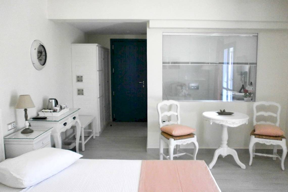 Innenansicht eines Schlafzimmers im Alkyoni Beach Hotel mit weißen Möbeln und Dekor.