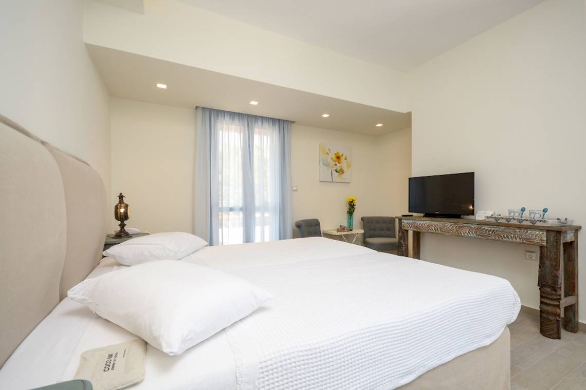 Schlafzimmer im Alkyoni Beach Hotel mit zwei Betten, Fernseher und Dekor.