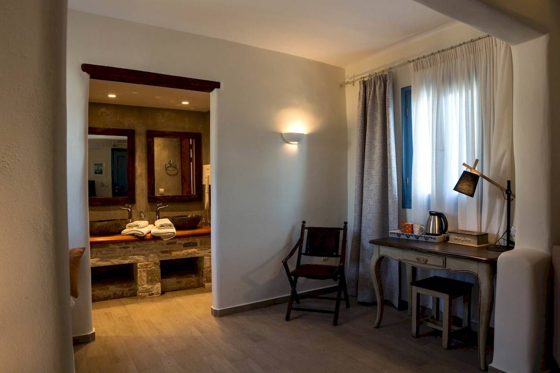 Innenansicht eines Zimmers im Alkyoni Beach Hotel mit Schreibtisch, Stuhl und Lampe.