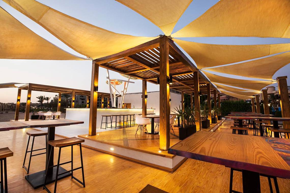 Terrasse des Pyramisa Beach Resort Sahl Hasheesh mit Tischen, Stühlen und Schattensegeln