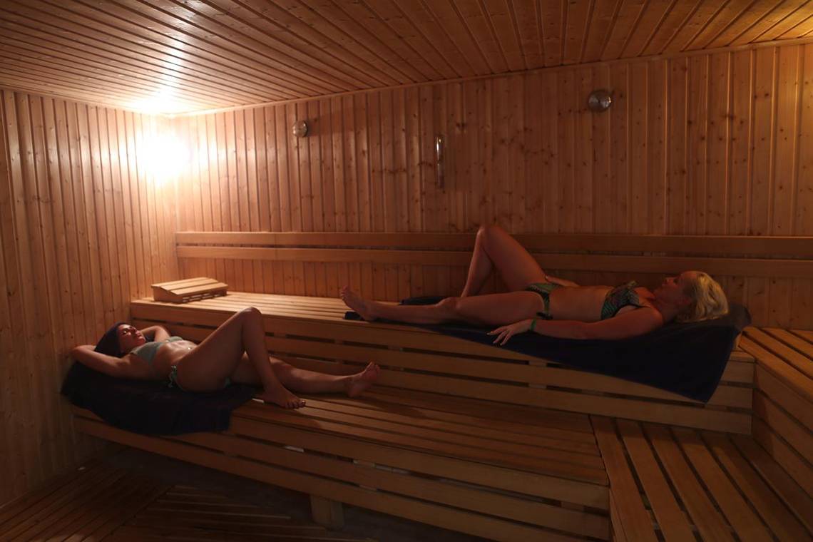Zwei Frauen entspannen sich in einer holzgetaefelter Sauna