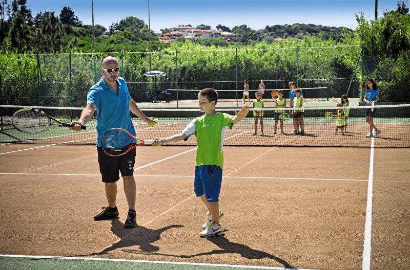 Tennistraining im Park Hotel Cala di Lepre mit einem Trainer und einem jungen Spieler.