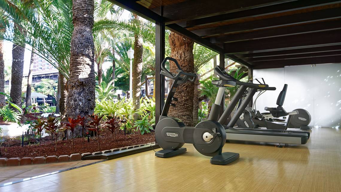 Fitnessgeräte im Fitnesscenter des Parque Tropical Hotels neben einem Garten