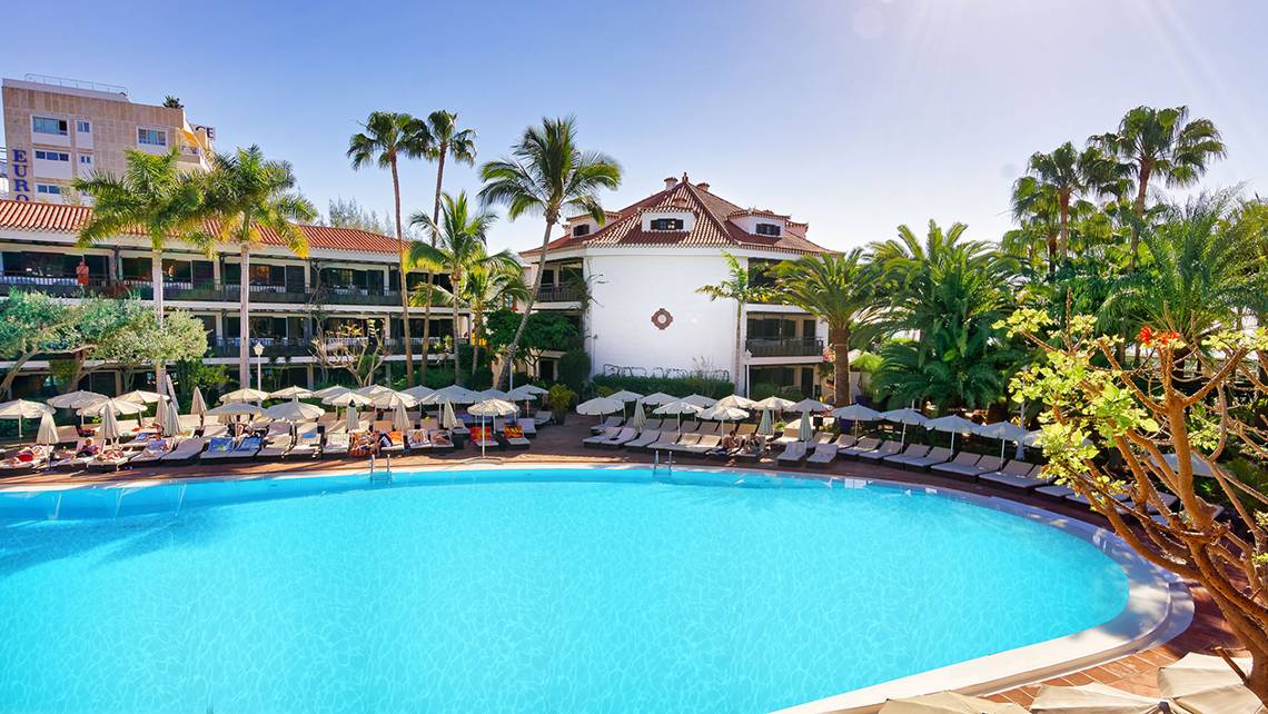 Außenansicht des Swimmingpools des Parque Tropical Hotels mit vielen Sonnenliegen und Palmen.