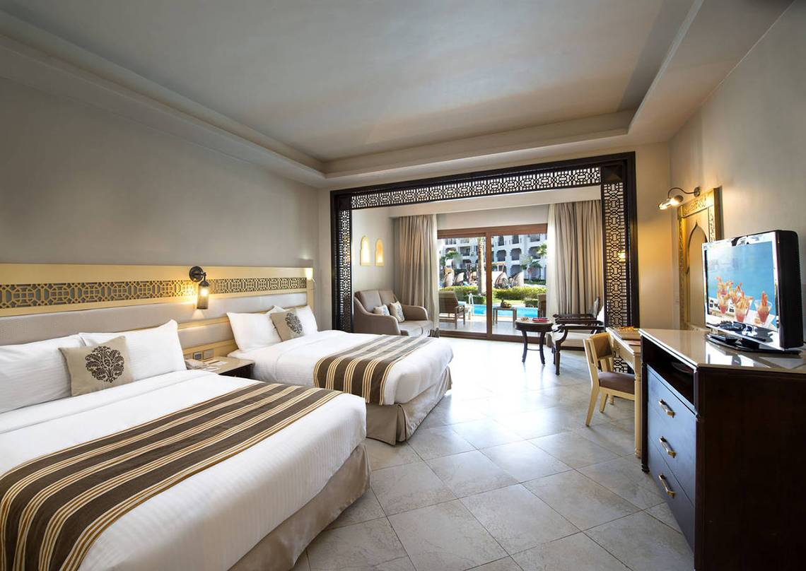 Doppelzimmer im Sunrise Arabian Beach Resort mit zwei Betten und Blick auf den Pool.