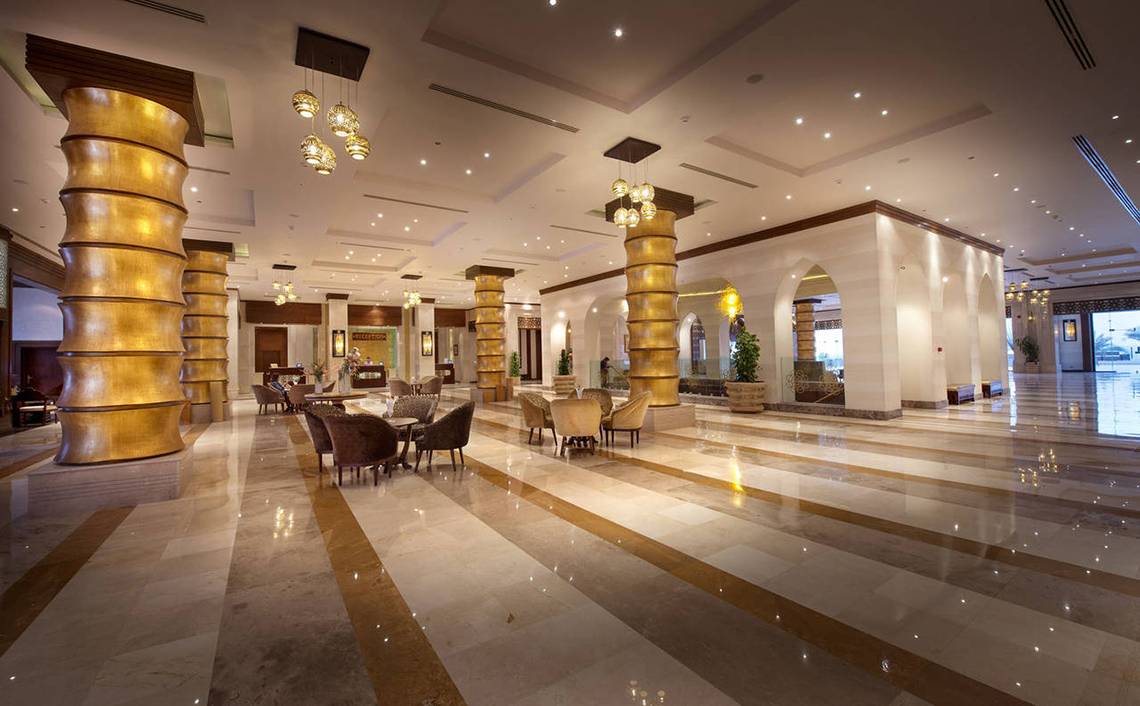 Lobby des Sunrise Arabian Beach Resorts mit goldenen Säulen und Möbeln.
